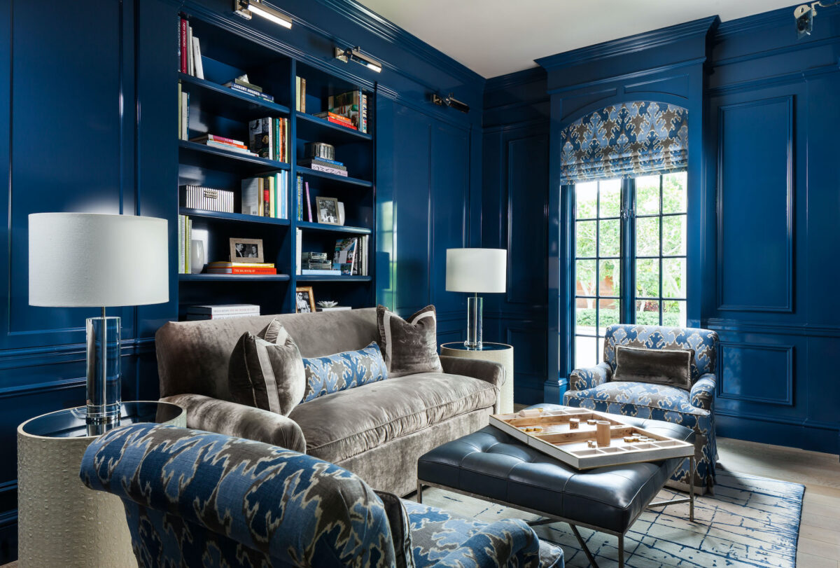 library with navy lacquered walls and dark sofa and chairs