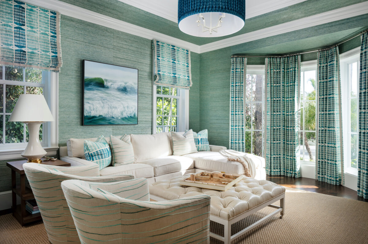 sitting room with white sofa and white tufted ottoman, teal wallpaper and teal curtains