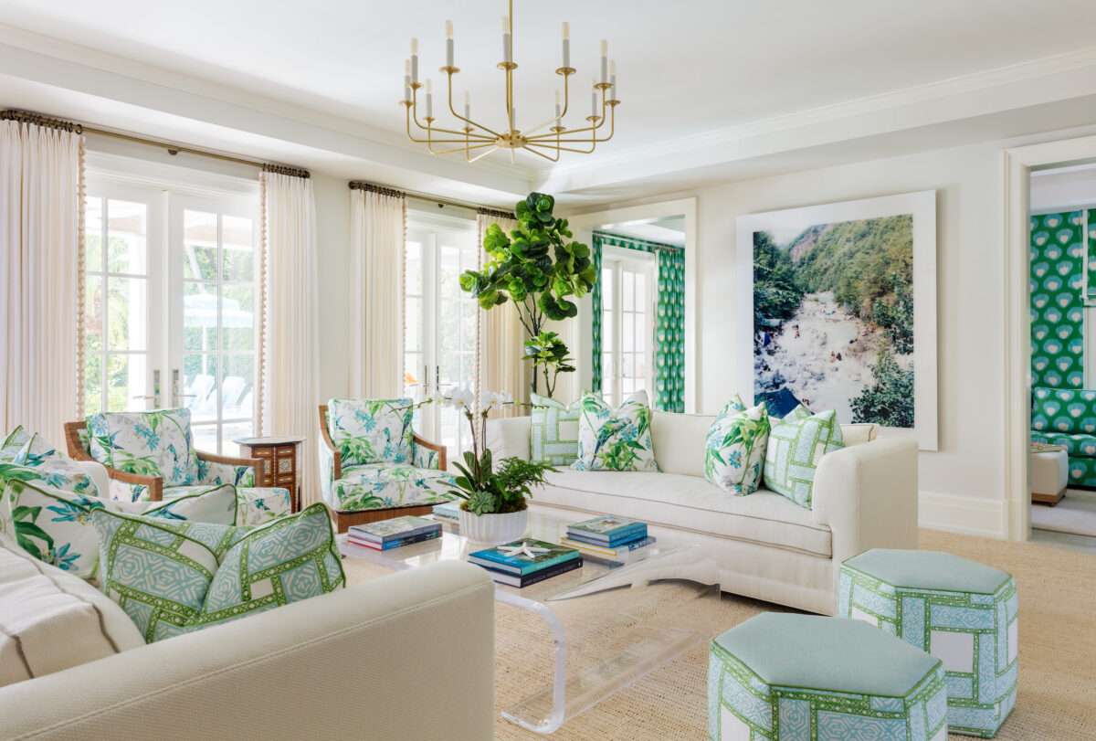 living room with white sofas, green and blue patterned chairs and ottomans, and french doors