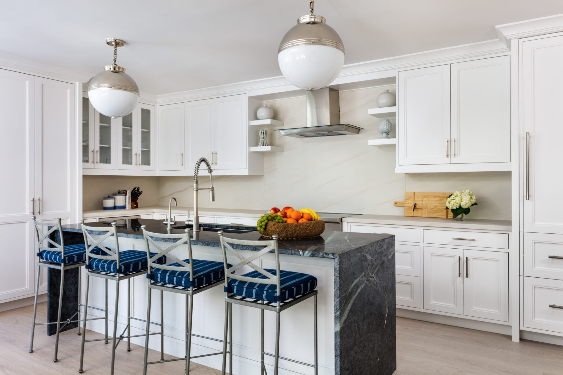 image of Winthrop House Condo kitchen with natural stone backsplash, white cabinets and large globe pendants