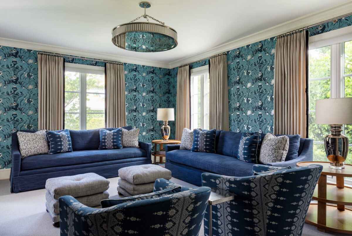 living room with blue sofas, blue patterned wallpaper and floor to ceiling windows