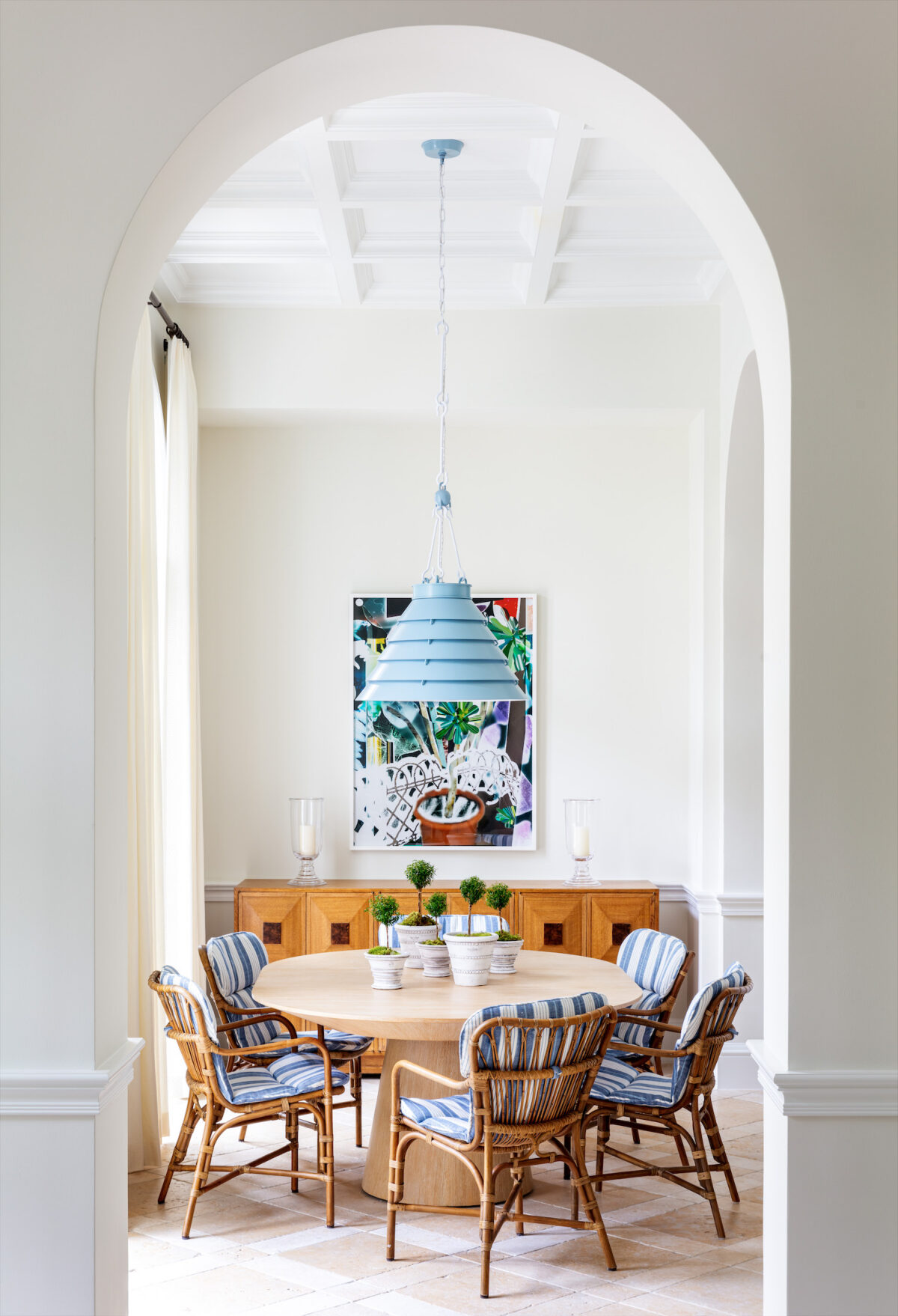 dining nook with rattan chairs with blue striped cushions and large blue overhead pendant light
