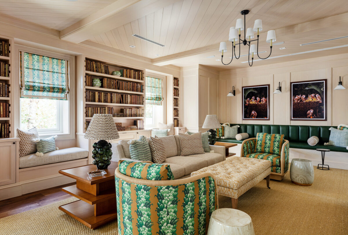 living room with neutral sofa and green and beige chairs and accents. Shelves hold brown books.