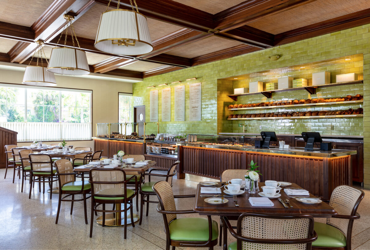 restaurant with green tile walls, dark wood counter, and tables with green cushion chairs
