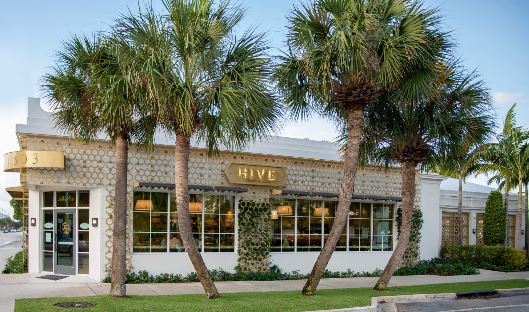 Image of Hive Bakery & Cafe Exterior Building with Gold Honeycomb Lattice and Palm Trees