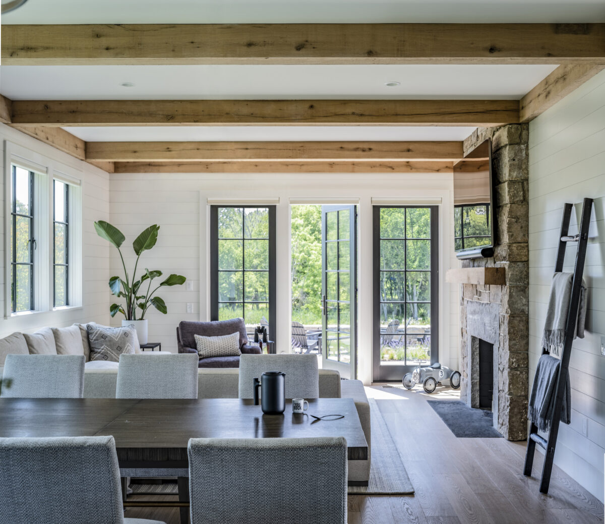 living room with wood ceiling beams and windows overlooking trees