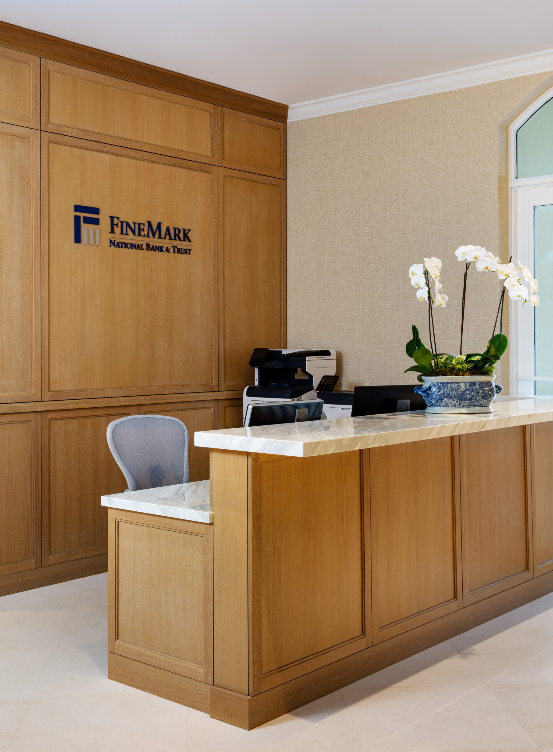 Reception desk with wooden cabinetry and blue and white planter with orchids