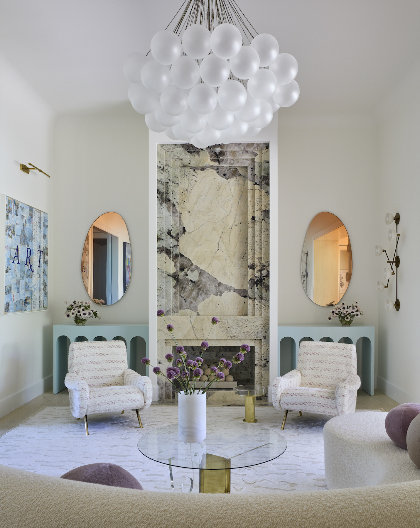 modern living room with fireplace, bauble chandelier, wall art, and white chairs