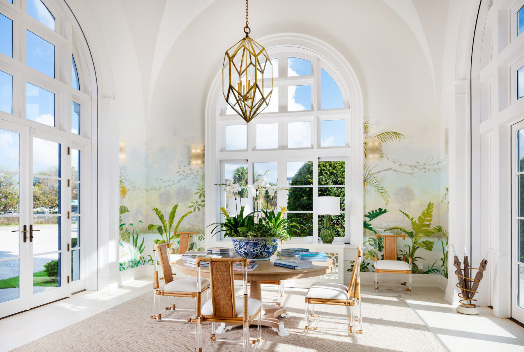 mccann design group studio with round table and bamboo chairs, tropical wall mural and tall arched windows